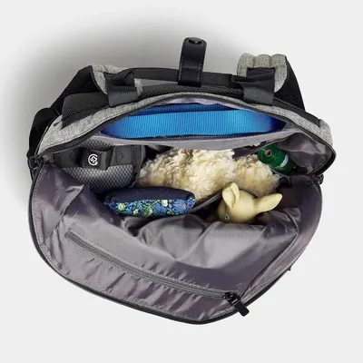Shows what fits inside the backpack and demonstrates its capacity by displaying pet toys, water bottle, and other accessories packed inside.