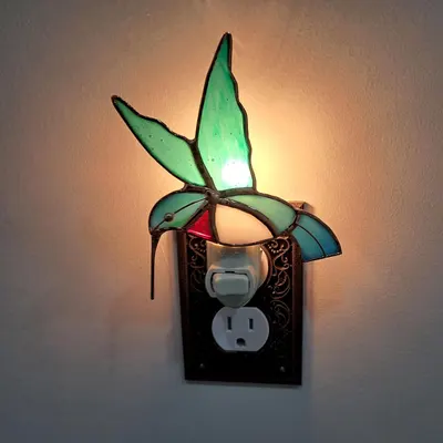 Shows the night light plugged in and illuminated in a real-world setting to demonstrate how it looks when in use.