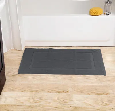 Displays the bath mat positioned in a bathroom setting near a tub, showing its intended placement and how it complements bathroom decor.