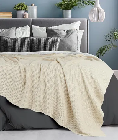 Shows the blanket in a real-world bedroom environment to help shoppers visualize how the product looks in use without any text or feature callouts.