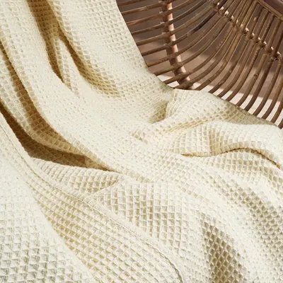 Showcases the waffle weave texture and drape of the blanket in a lifestyle setting to help shoppers appreciate the material quality and visual appeal.