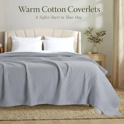 Showcases the product in a real-world bedroom environment to help shoppers visualize how the coverlet looks and feels in their own home.