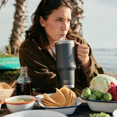 Displays the product in use during an outdoor beach picnic setting to help shoppers envision the drinkware as part of their outdoor dining and leisure…