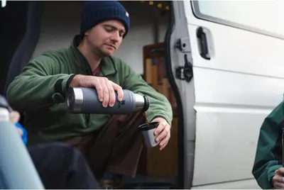 Demonstrates the thermos in a real-world outdoor setting to help shoppers visualize using it during camping or travel adventures.