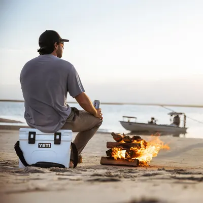 Shows the product being used as a seat at the beach during a campfire, demonstrating its versatility and durability in outdoor leisure settings.