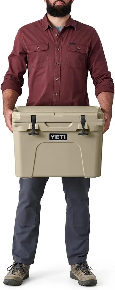 Uses a human figure holding the cooler to provide a visual scale reference, helping shoppers understand the product's physical size and portability.