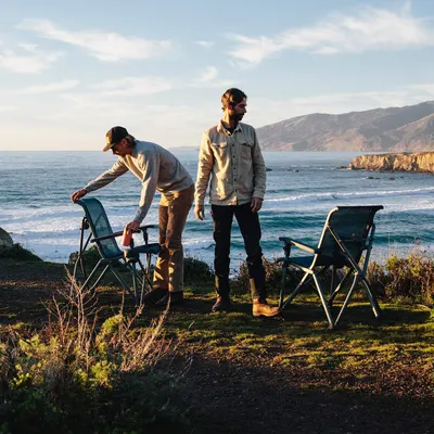 Shows the chairs being used in a scenic coastal outdoor setting to help shoppers envision the product in their own adventures.