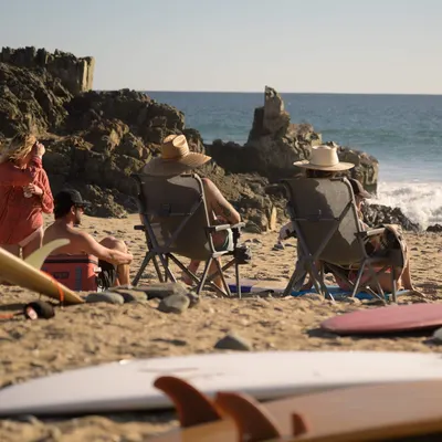 Depicts the chairs in use at the beach to demonstrate the product's versatility and appeal for beach-going shoppers.