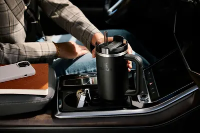 Demonstrates the product fitting in a car cupholder to reassure shoppers it works for commuting and travel.