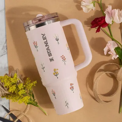 Presents the tumbler in an aesthetic lifestyle setting with flowers and natural elements, appealing to shoppers looking for a stylish, giftable product.