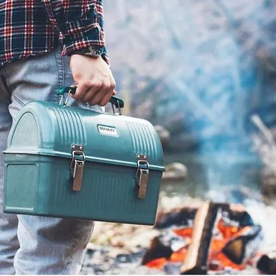 Shows the lunch box being carried outdoors in a natural setting, emphasizing its portability and suitability for outdoor activities.
