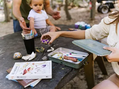 Shows the product being used to organize art supplies in a family outdoor setting, demonstrating practical everyday use.