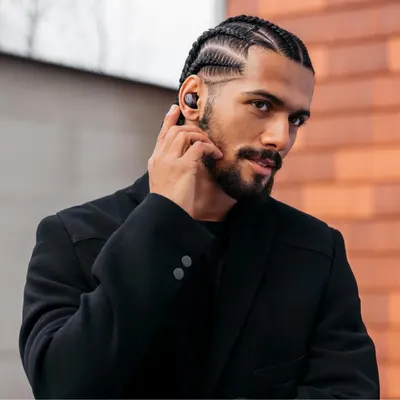 Shows a man wearing the earbuds in an urban setting to help shoppers picture using them in daily life.