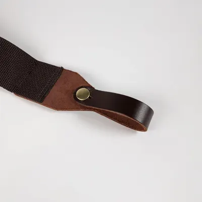 Shows the strap's leather end loop and brass snap up close on a plain background to confirm build quality.