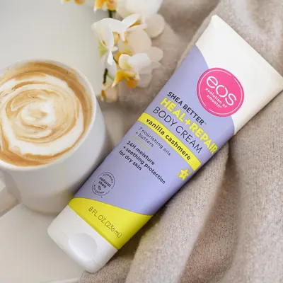 Shows the cream in a warm home setting beside a latte and soft fabric. Helps shoppers picture it as part of a relaxed routine.