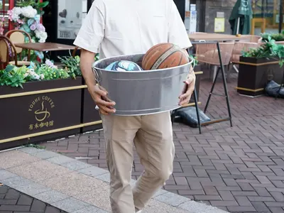 Shows a person casually carrying the tub with balls inside, suggesting easy portability in a real setting.