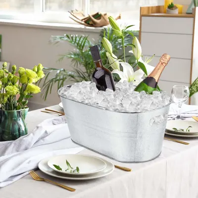 Shows the tub styled on a dining table with ice and bottles for an elegant entertaining look.