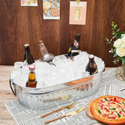 Shows the galvanized tub filled with ice and drinks in a real dining setting so shoppers can picture it at their own gatherings.