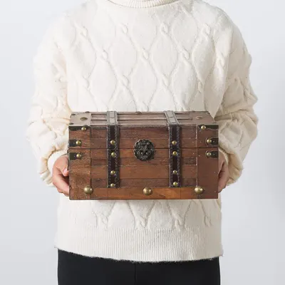 Shows a person holding the vintage wooden trunk with no text overlay, letting shoppers picture its size and rustic style in hand.