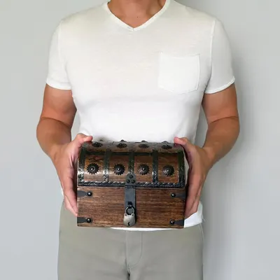 Shows the treasure chest being held by a person to convey its handheld size and rustic pirate style without any text overlay.